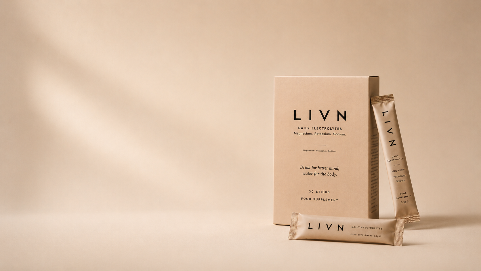LIVN Daily Electrolyte powder supplement packaging, featuring a beige cardboard box with black text alongside two individual stick packs, arranged on a matching beige background with soft shadow overlays.